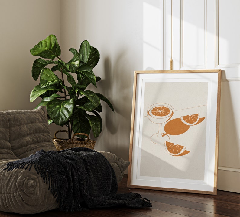 Peut inclure: Une impression d'art minimaliste repr&eacute;sentant une illustration stylis&eacute;e d'un verre avec une tranche d'orange et deux tranches d'orange sur un fond beige.
