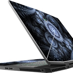 May include: A black laptop with a silver lid. The lid has a black and white abstract design. The laptop is open and the keyboard is visible. The laptop is sitting on a white surface.