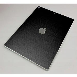 May include: A black tablet with a brushed metal texture and a silver Apple logo in the center. The tablet has a silver border and a camera lens at the top. The overall design is sleek and modern.