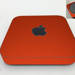 May include: A bright orange Apple Mac mini computer with a black Apple logo on the front.