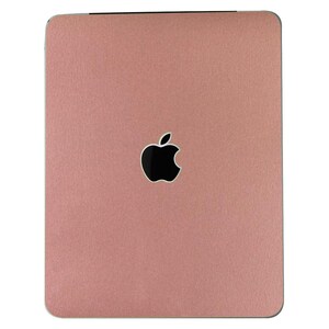 May include: A rose gold laptop skin with the Apple logo in the center.