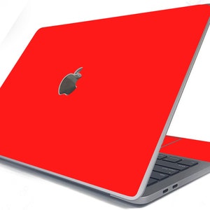 May include: A red laptop computer with a silver Apple logo on the lid. The laptop is closed and the screen is facing away from the viewer.