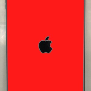 Puede incluir: Un iPad rojo con un logotipo de Apple negro en la parte posterior.
