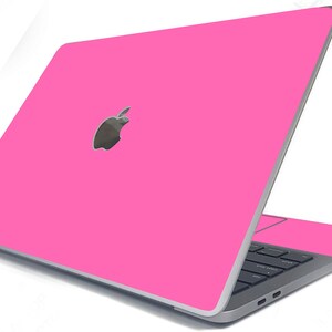 May include: A pink laptop computer with a silver Apple logo on the lid. The laptop is closed and the screen is facing away from the viewer.