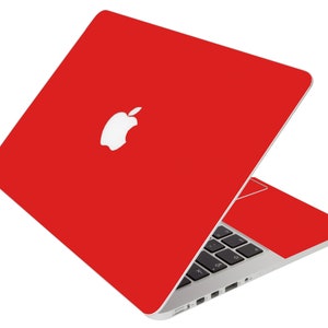 May include: A red laptop computer with a white Apple logo on the lid. The laptop is open and the keyboard is visible.