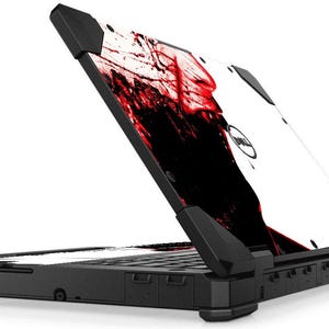 May include: A black laptop computer with a white and red splatter design on the lid. The laptop is closed and the lid is open to a 45-degree angle.