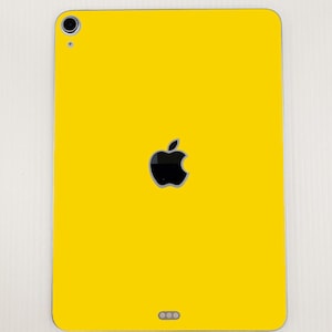 May include: A yellow iPad with a black Apple logo and a black camera lens.