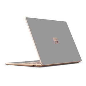 Op de afbeelding: Een grijze laptop met een roségouden rand. De laptop is gesloten en het Microsoft-logo is zichtbaar op de deksel.