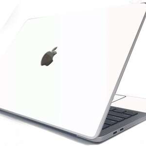 May include: A white laptop computer with a silver Apple logo on the lid. The laptop is closed and the screen is facing away from the viewer.