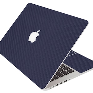 May include: A navy blue laptop with a carbon fiber texture skin. The Apple logo is visible on the lid. The keyboard and trackpad are also visible. The laptop is open, showing the screen and keyboard.