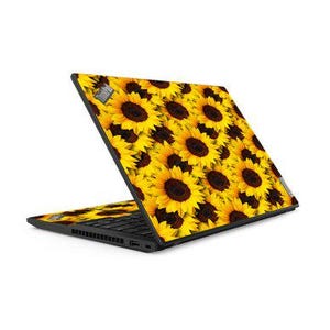 May include: Black laptop with a vibrant sunflower pattern on the lid and keyboard area. The design features bright yellow petals and dark brown centers, creating a cheerful and eye-catching aesthetic. The laptop is open, displaying the keyboard.