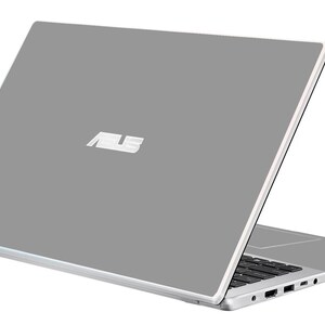 Könnte beinhalten: Ein silberner ASUS-Laptop mit grauem Deckel, leicht geöffnet, um die Tastatur und Anschlüsse freizulegen. Das ASUS-Logo ist auf dem Deckel sichtbar. Der Laptop befindet sich auf weißem Hintergrund.