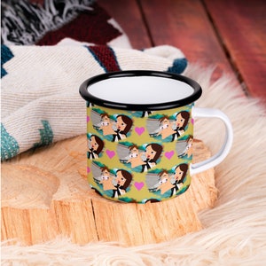 May include: A white enamel mug with a black rim and handle. The mug features a repeating pattern of cartoon characters kissing, with pink hearts in between.
