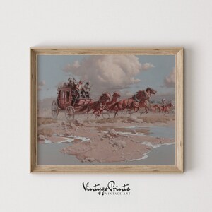 May include: A framed vintage print shows a stagecoach drawn by six horses, speeding across a desert scene. The artwork features a red stagecoach, riders, and Native Americans in the background. The print is framed in a light brown wooden frame.