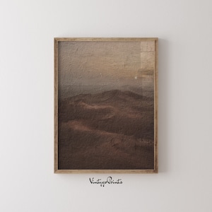 Puede incluir: Una impresi&oacute;n enmarcada de una pintura de paisaje en tonos marrones y beige. La pintura representa un paisaje de colinas onduladas con un cielo brumoso en el fondo.