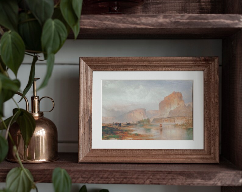 May include: A framed landscape painting depicting a river flowing through a canyon with a mountain in the background. The painting is in a rustic wooden frame.