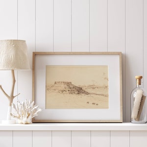 May include: A framed black and white drawing of a landscape with a mountain range in the distance. The drawing is on a white background and is framed in a light wood frame. The frame is sitting on a white shelf with a white lamp and a glass bottle with a cork stopper.