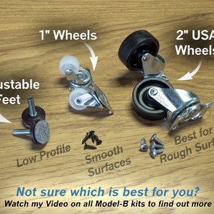 May include: A close-up of four different types of furniture casters, including 1-inch wheels, 2-inch USA wheels, adjustable feet, and screws. The casters are on a wood surface. "Not sure which is best for you? Watch my Video on all Model-B kits to find out more." is written at the bottom of the image.