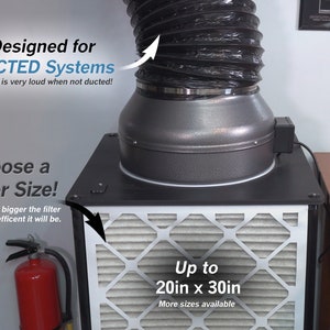 May include: A black and gray air filter system with a black flexible duct attached. The system is designed for ducted systems and can accommodate filters up to 20 inches by 30 inches. The text "Designed for DUCTED Systems" and "The fan is very loud when not ducted!" is visible in the image. The text "Choose a Filter Size!" and "NOTE: The bigger the filter the more efficient it will be." is also visible in the image. The text "Up to 20in x 30in" and "More sizes available" is visible in the image.