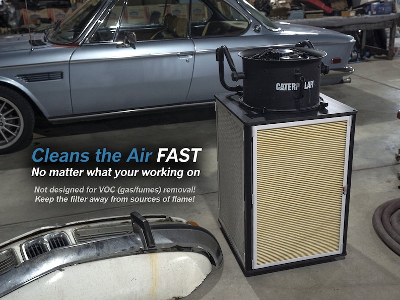 May include: A black air purifier with a large fan and a yellow filter. The text "CATERP LAR" is visible on the front of the purifier. The text "Cleans the Air FAST" is visible in the image. The text "No matter what your working on" is visible in the image. The text "Not designed for VOC (gas/fumes) removal!" is visible in the image. The text "Keep the filter away from sources of flame!" is visible in the image.