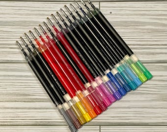 May include: A set of 18 colorful gel ink pen refills. The refills are black, red, orange, yellow, green, blue, purple, and pink. The refills are arranged in a fan shape, with the black refills at the top and the pink refills at the bottom.