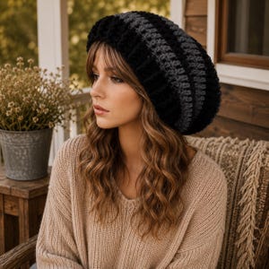 Puede incluir: Un gorro de punto grueso con rayas horizontales alternas de hilo negro y gris oscuro. El gorro tiene una construcción acanalada gruesa y texturizada con una silueta holgada que cubre la parte superior de la cabeza y las orejas.