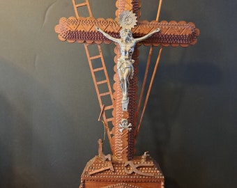 May include: A wooden crucifix with a silver Jesus figure. The crucifix is intricately carved with a ladder, spear, and other symbols. The base of the crucifix is also carved with intricate details.