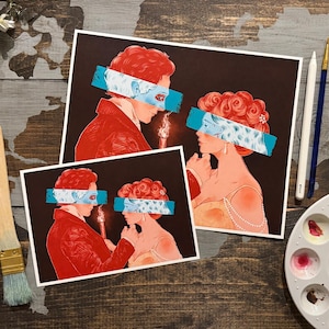 Puede incluir: Dos impresiones artísticas con ilustraciones de un hombre y una mujer de perfil, con una vela entre ellos. El hombre lleva un abrigo rojo y la mujer un vestido amarillo. Ambos tienen los ojos cubiertos con una franja azul y blanca. Las impresiones están sobre un fondo oscuro.
