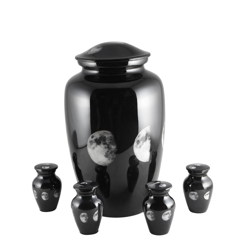 May include: A set of five black urns with a moon phase design. The largest urn is taller than the four smaller urns. The urns are made of metal and have a shiny finish.