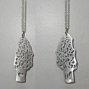 May include: Two silver necklaces with a detailed tree-shaped pendant. Each pendant has a heart-shaped cutout at the bottom.