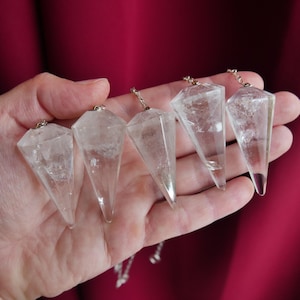May include: Five clear, faceted, pointed crystal pendants, each attached to a small silver-toned metal chain link. The crystals are transparent with internal inclusions and have a geometric, multi-sided shape that tapers to a sharp point.