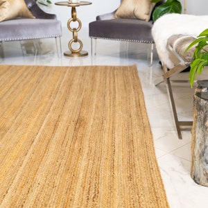 May include: A natural fiber rug made from jute, a sustainable and durable material. The rug has a light brown color and a woven texture. It is perfect for adding a touch of natural beauty to any room.