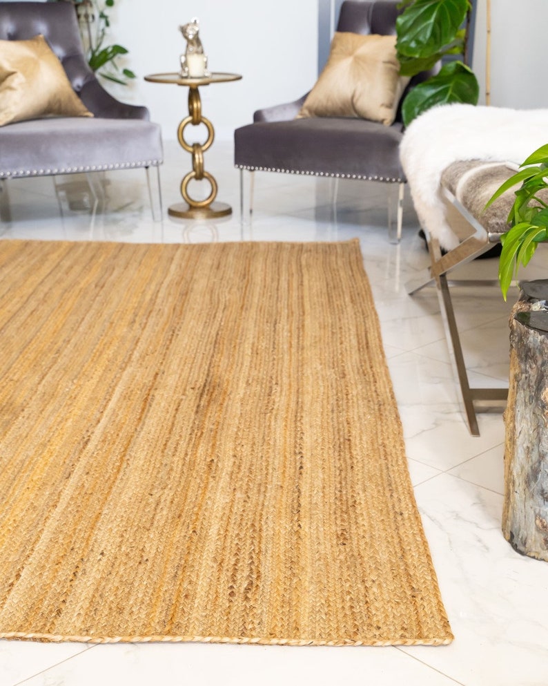 May include: A natural fiber rug made from jute, a sustainable and durable material. The rug has a light brown color and a woven texture. It is perfect for adding a touch of natural beauty to any room.