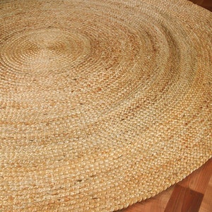 May include: A round, natural fiber rug made from jute. The rug has a woven texture and a light brown color.