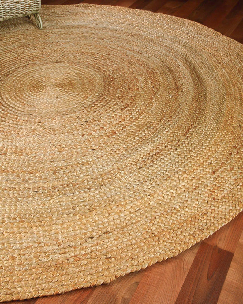 May include: A round, natural fiber rug made from jute. The rug has a woven texture and a light brown color.