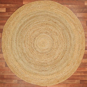May include: A round, natural fiber rug with a woven pattern. The rug is beige and has a circular shape.