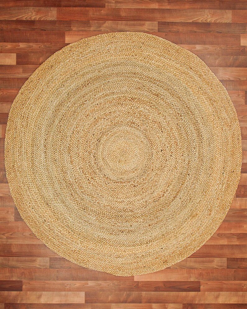 May include: A round, natural fiber rug with a woven pattern. The rug is beige and has a circular shape.