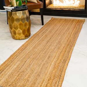 May include: A natural fiber runner rug in a light brown color. The rug has a woven texture and is made of jute.