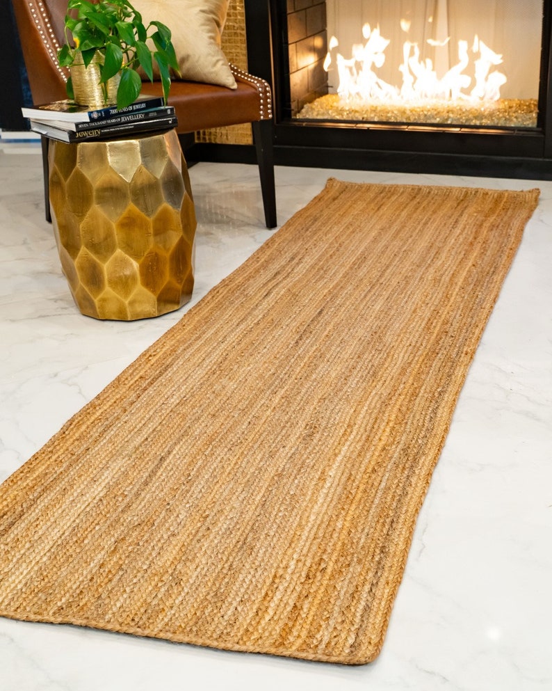 May include: A natural fiber runner rug in a light brown color. The rug has a woven texture and is made of jute.