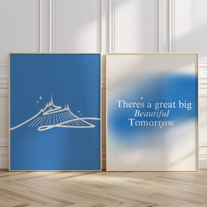 Op de afbeelding: Twee blauwe en witte ingelijste prints. De linker print toont een witte omtrek van een futuristisch gebouw met een witte weg die ernaartoe leidt. De rechter print toont een witte tekstoverlay op een blauwe en witte gradiëntachtergrond die "There's a great big Beautiful Tomorrow" luidt.