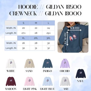 Op de afbeelding: Een marineblauwe hoodie met een grafisch ontwerp en maattabel. De hoodie is verkrijgbaar in verschillende kleuren, waaronder wit, zand, indigo, orchidee, bordeaux, lichtroze, lichtblauw, as en marine. De maattabel toont de afmetingen in cm.
