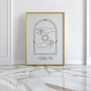 May include: A black and white line art print of two hands reaching towards a sun inside an archway. The print has a gold frame and the text "STARBORN" at the bottom.