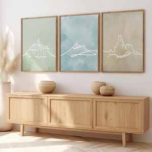 Puede incluir: Tres impresiones artísticas enmarcadas con dibujos lineales blancos de paisajes montañosos sobre fondos pastel verdes, azules y beiges. Las impresiones están sobre un mueble de madera con jarrones decorativos.