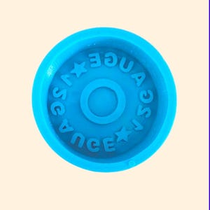 May include: A round, bright blue mold with the word "SAUCE" and a star shape repeated around the outer edge. The word "AQUA" is also visible. A central circle is in the middle of the mold.