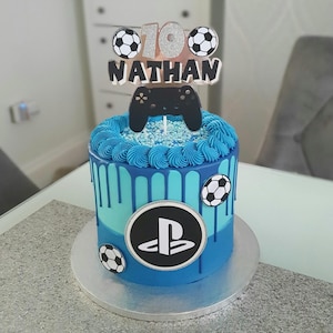 May include: A blue and turquoise drip cake with a PlayStation logo, footballs, and a topper that says "10 Nathan" with a video game controller.