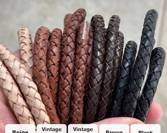 Puede incluir: Primer plano de cordones de cuero trenzado en varios colores: beige, marrón vintage, marrón vintage, marrón y negro. Cada cordón está tejido apretadamente, mostrando la textura y la artesanía. Se incluyen etiquetas con los nombres de los colores.