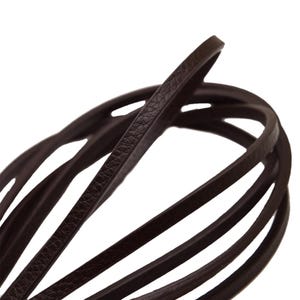 Puede incluir: Primer plano de un cordón de cuero marrón oscuro, enrollado y en capas. El cuero tiene una superficie texturizada y está dispuesto en un patrón circular. El cordón parece nuevo y sin usar.