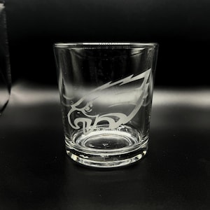 May include: A clear glass tumbler with an etched design of a white eagle's head.