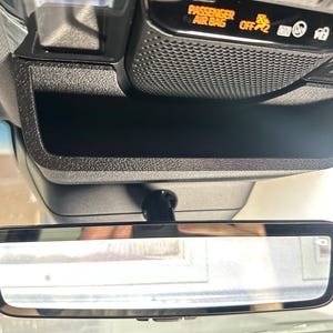 May include: A black overhead console in a vehicle featuring a storage compartment, a rearview mirror, and an illuminated display panel with the text PASSENGER AIR BAG OFF and various indicator icons for safety and vehicle status.