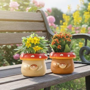 May include: Two mushroom-shaped planters with plants. The planters are beige and orange with red tops and white polka dots. Each planter has a pair of hands holding a coffee cup. One planter has yellow flowers, and the other has orange flowers.